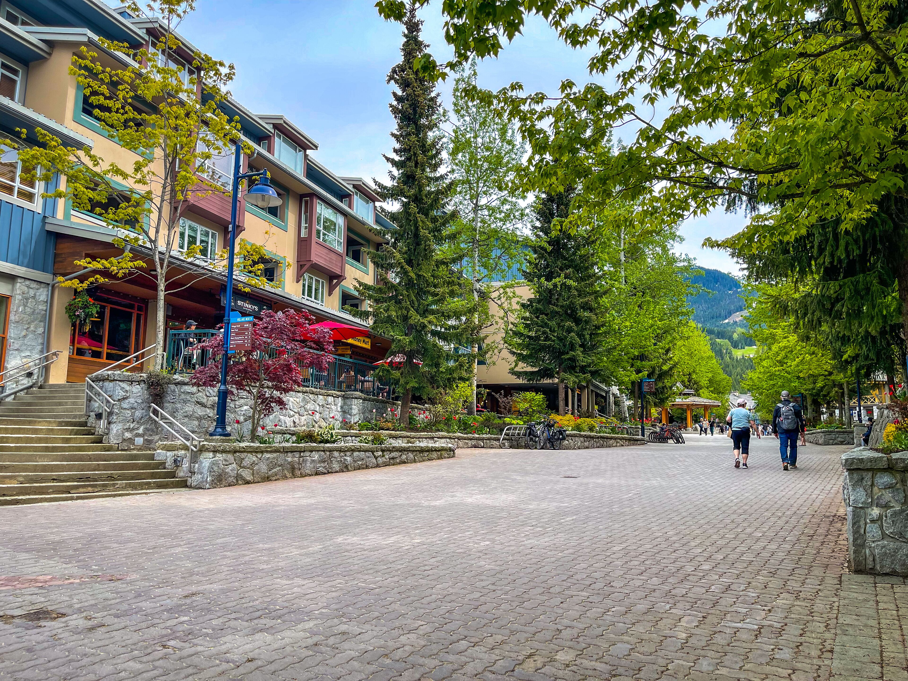 A paved street with buildings, a stone staircase, and a mountain in the background.