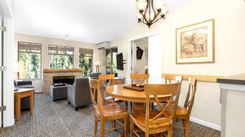 A dining area with a round wooden table and chairs, a chandelier, and a framed picture on the wall.