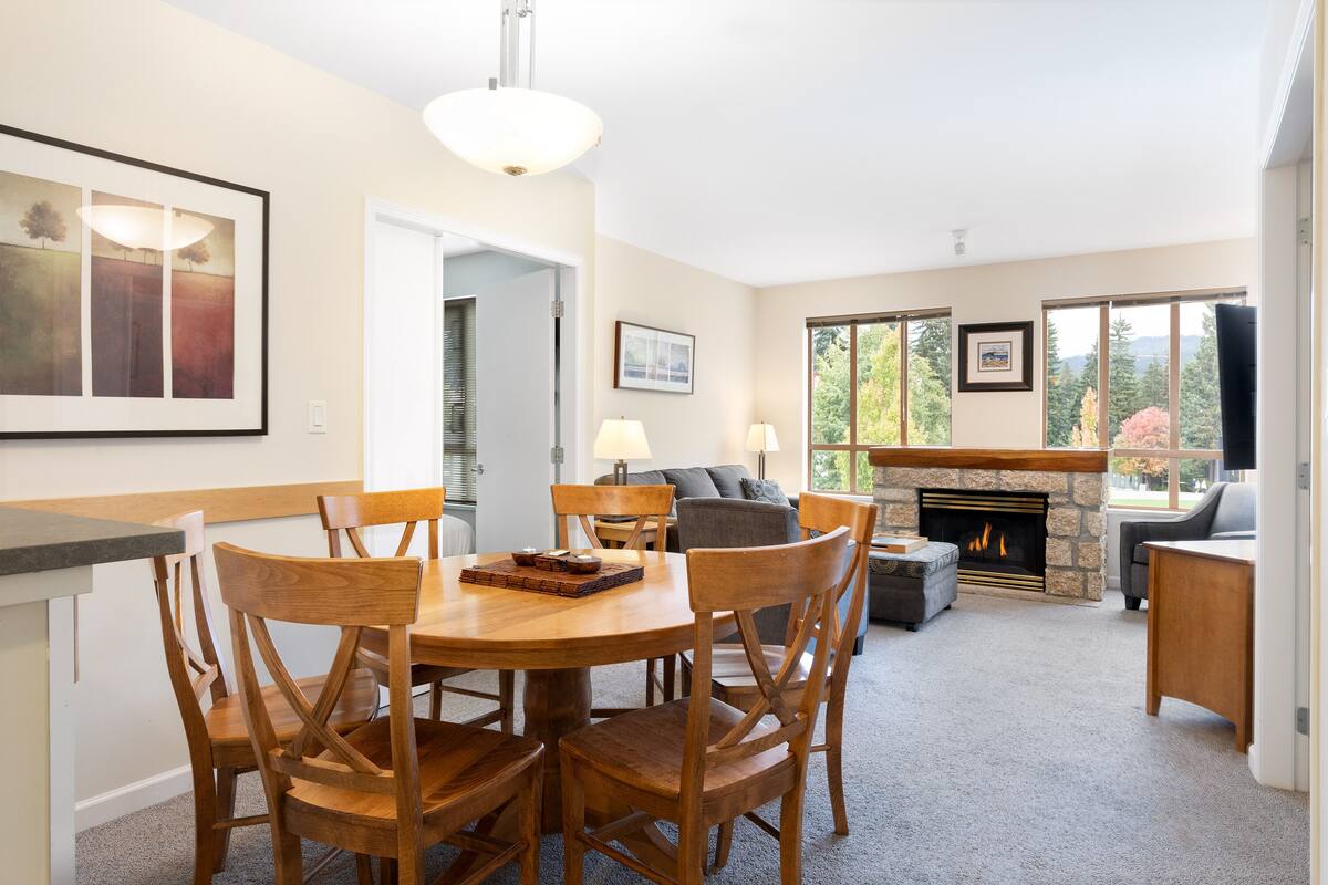 A spacious living area with a fireplace, a dining table with chairs, and a sofa.