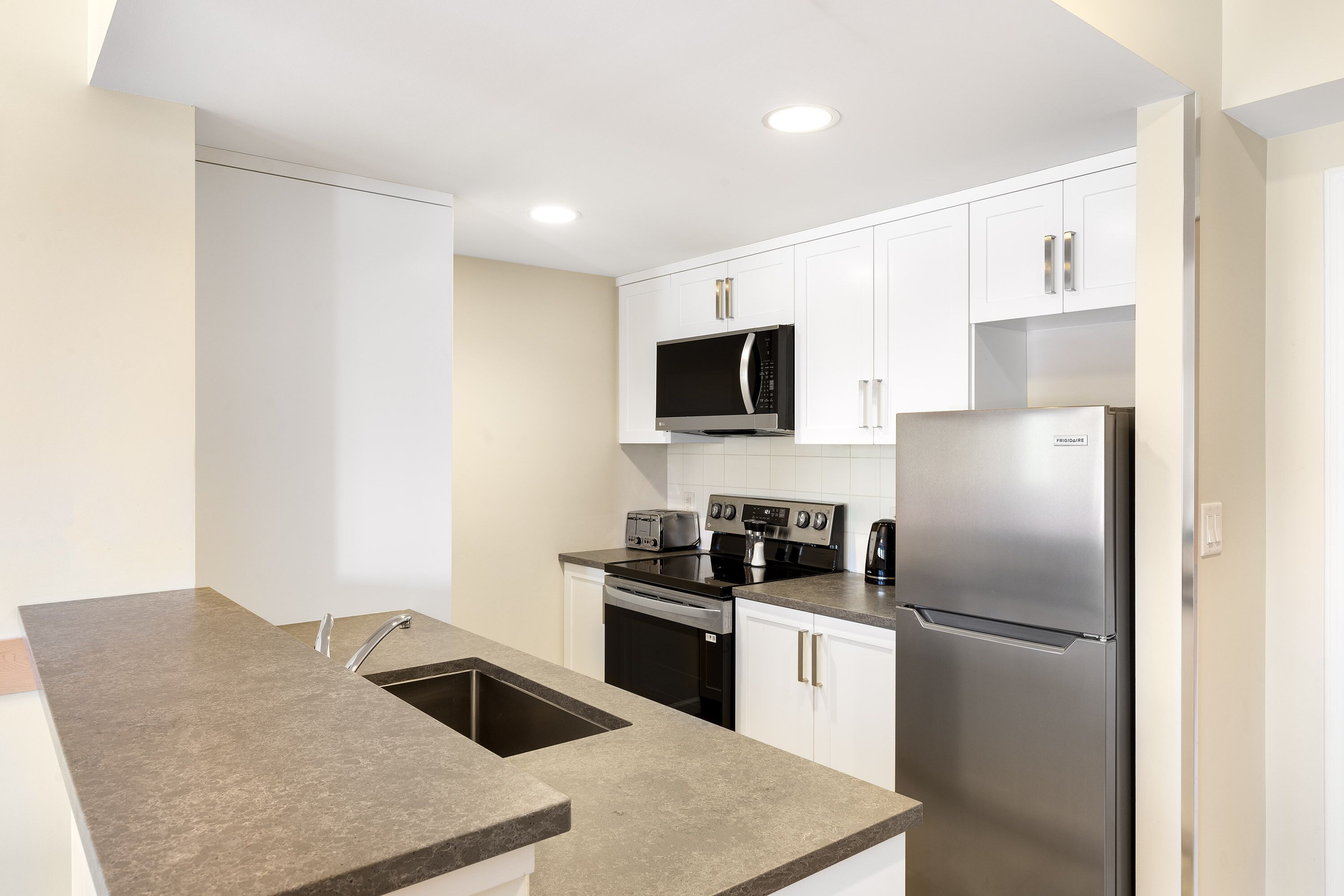 A modern kitchen with white cabinets, stainless steel appliances, and a granite countertop.