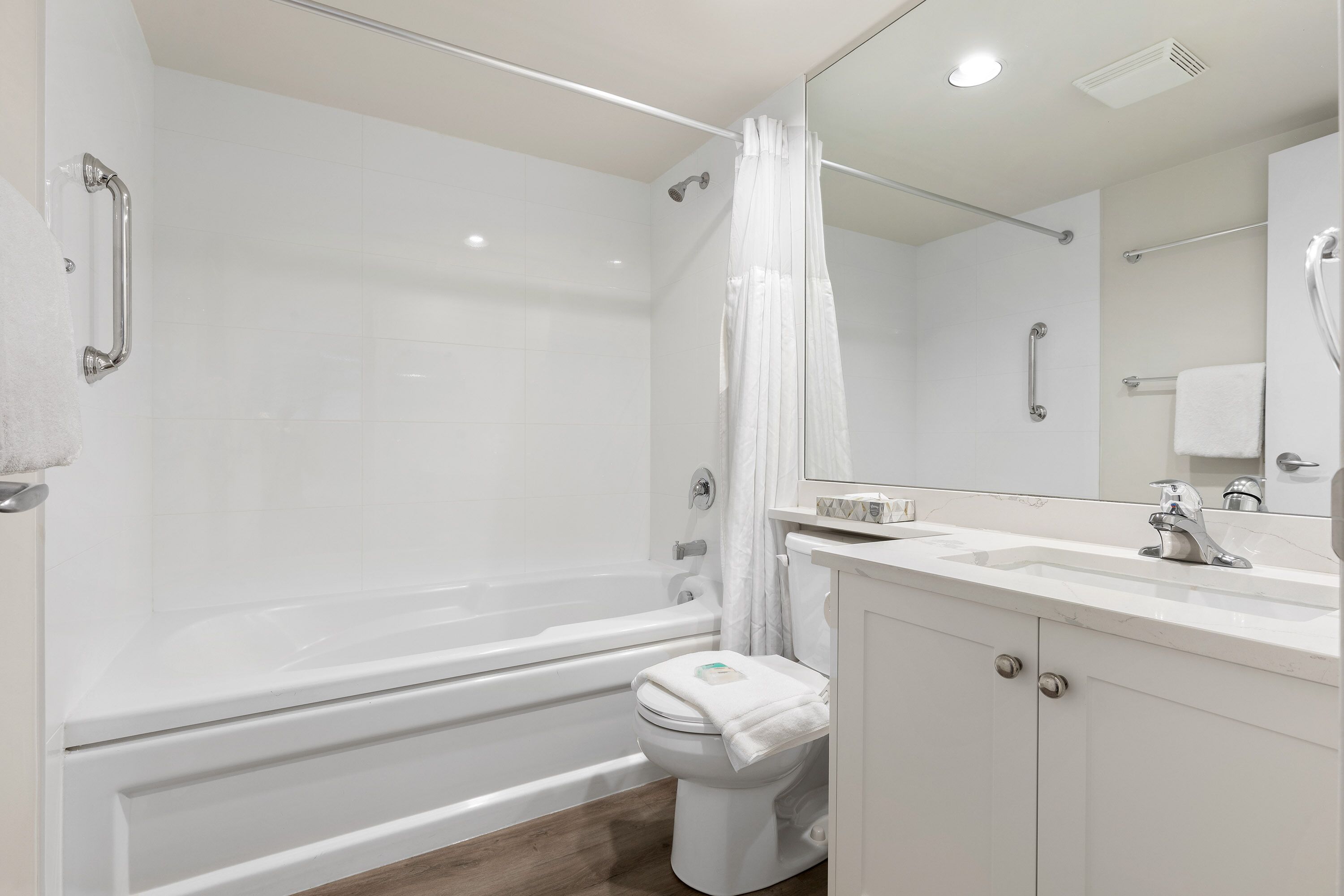Une salle de bain moderne avec une baignoire, des toilettes et un lavabo, le tout de couleur blanche.