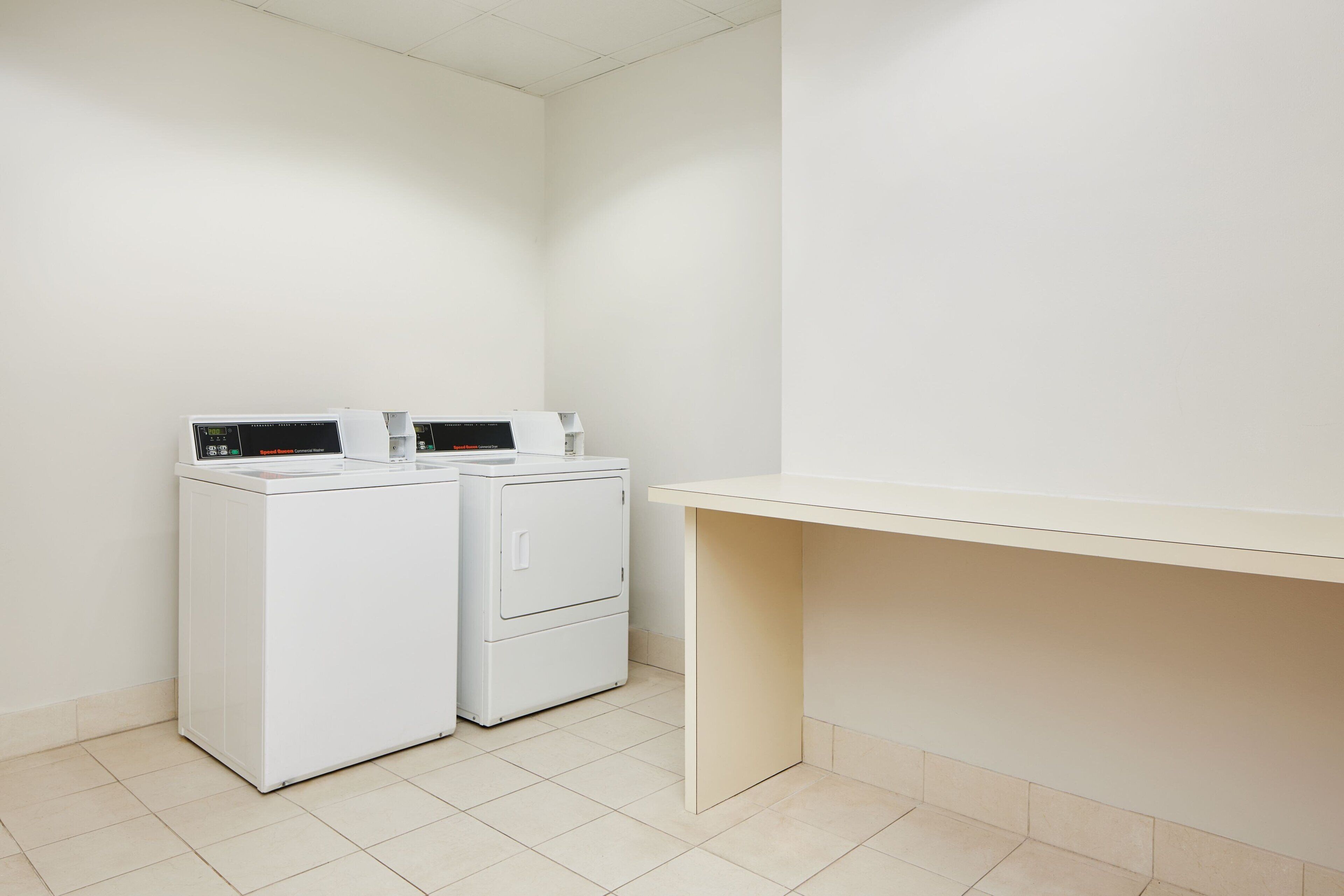 Un espace buanderie avec deux machines à laver blanches et un banc beige.