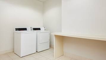 Un espace buanderie avec deux machines à laver blanches et un banc beige.