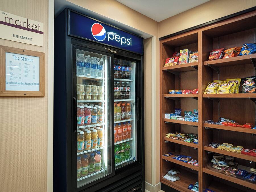 A vending machine stocked with Pepsi and other beverages, and shelves with snacks and other food items.