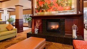 A lobby with a fireplace, a sofa, and a large painting above the fireplace.