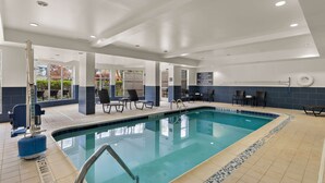 An indoor swimming pool with clear water, surrounded by lounge chairs and a poolside bar. - Hilton Garden Inn Atlanta East/Stonecrest (Lithonia)