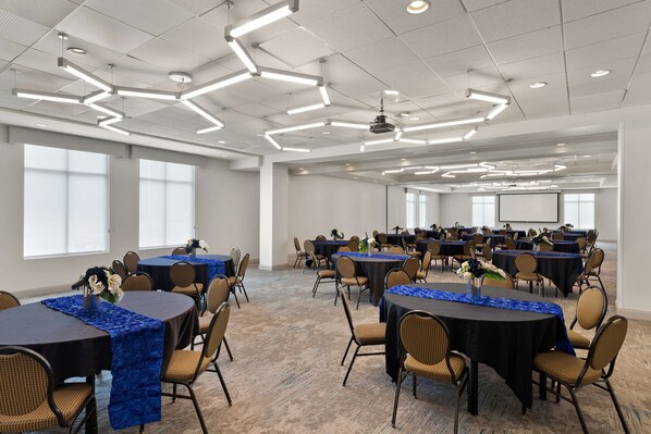A conference room with multiple tables, chairs, and a projector screen.