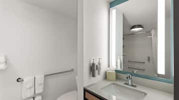 Un baño moderno con un lavabo blanco, un espejo grande y una cabina de ducha de vidrio.