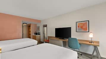 A hotel room with two beds, a desk with a computer, a TV, a chair, and a desk lamp.