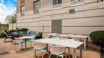 Eine Terrasse im Freien mit einem weißen Tisch und Stühlen, einer Couch und Lichterketten.