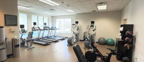 A gym with treadmills, elliptical machines, and exercise balls.