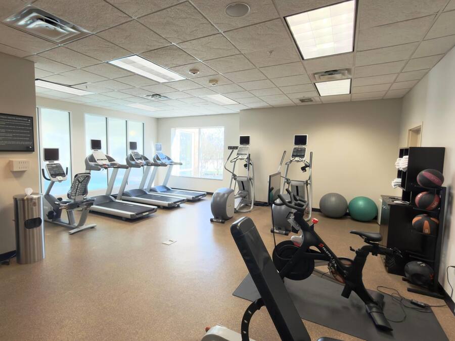 A gym with treadmills, elliptical machines, and exercise balls.