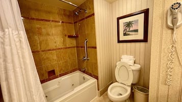 A bathroom with a bathtub, toilet, shower, and a telephone.