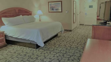 Een hotelkamer met een bed, een bureau, een lamp, een schilderij en een deur.