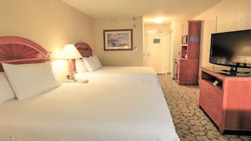 A hotel room with two beds, a television, a desk, and a cabinet.