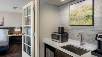 A modern kitchen with a microwave, sink, and a painting on the wall.