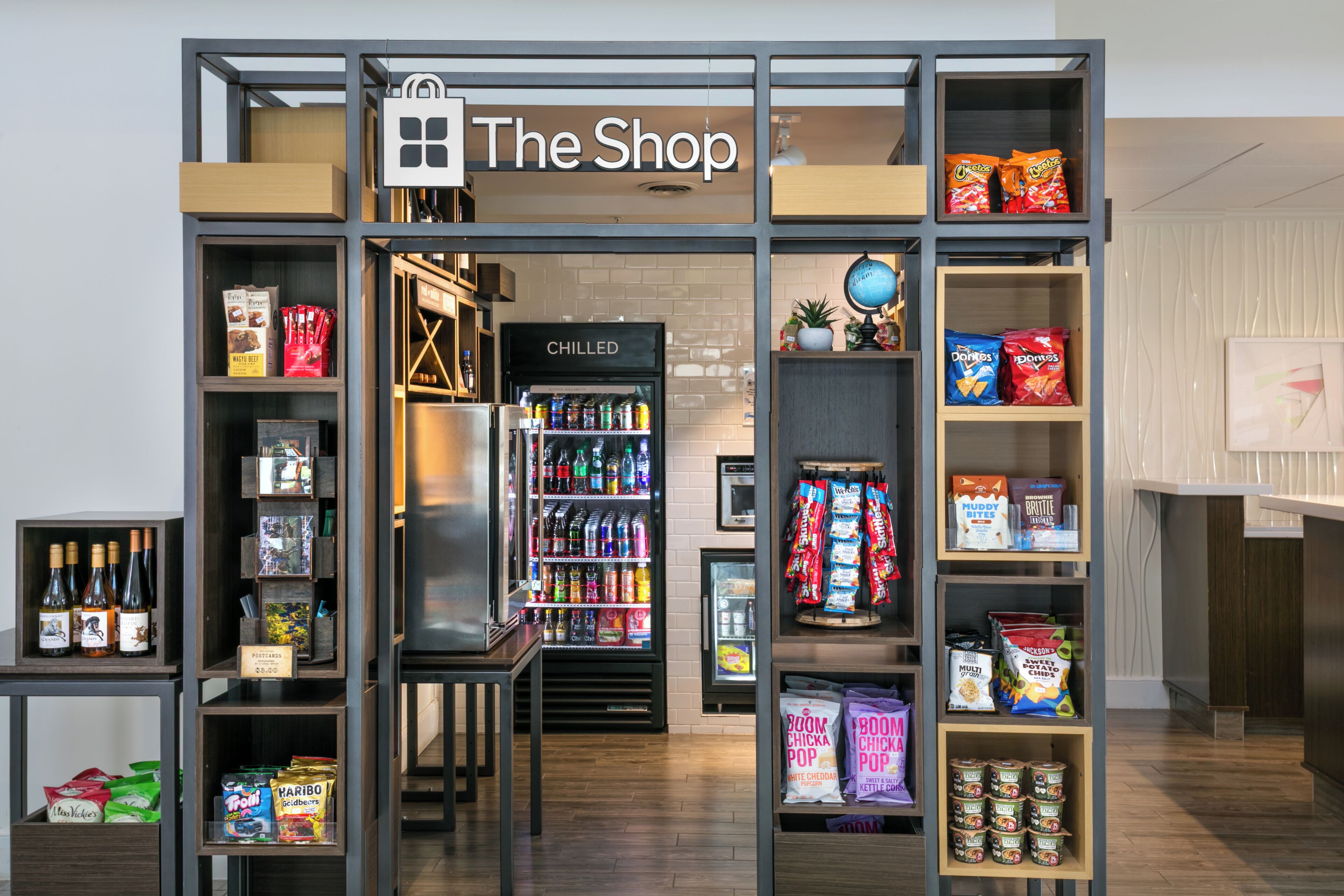 Una tienda llamada 'The Shop' con estantes llenos de aperitivos, bebidas y otros artículos.