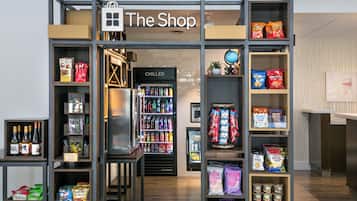 Una tienda llamada 'The Shop' con estantes llenos de aperitivos, bebidas y otros artículos.