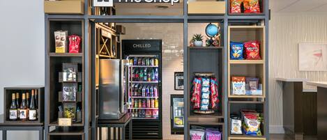 Una tienda llamada 'The Shop' con estantes llenos de aperitivos, bebidas y otros artículos.