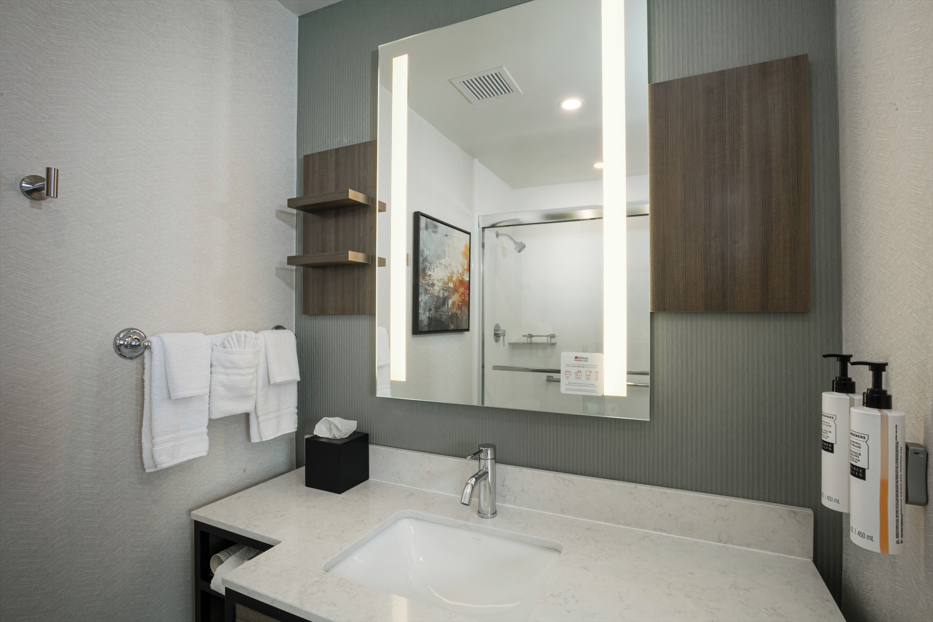 A modern bathroom with a large mirror, a sink, and a shower.