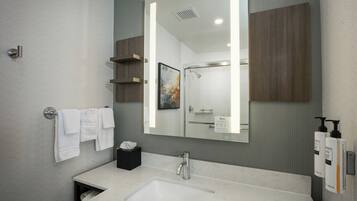 A modern bathroom with a large mirror, a sink, and a shower.