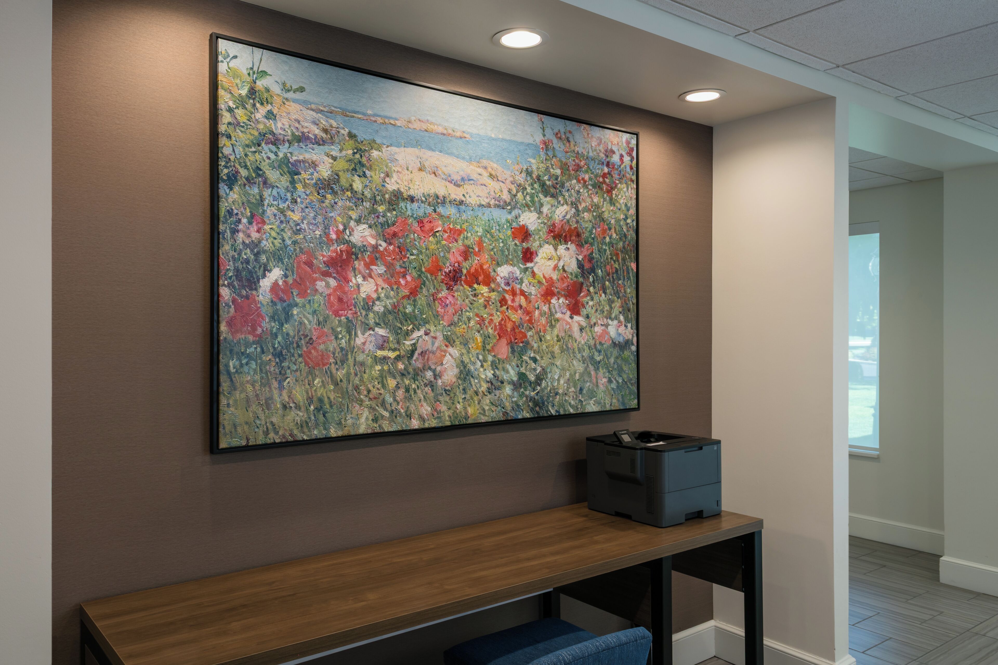 Et værelse med et stort blomsterbillede på væggen, en træbænk og en printer på bænk.