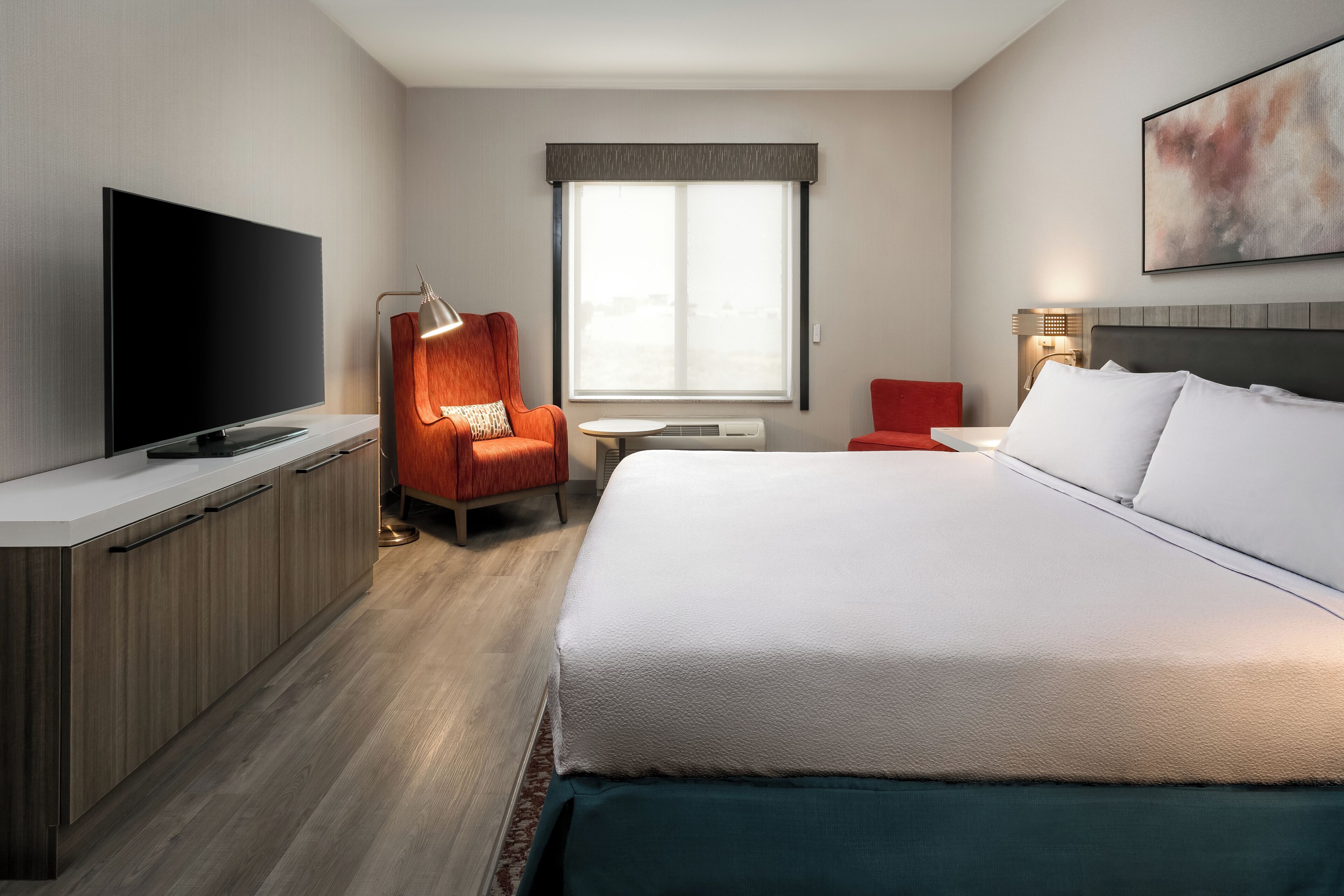 Een hotelkamer met een bed, een televisie, een bureau en een stoel.