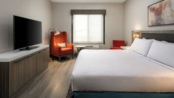 Een hotelkamer met een bed, een televisie, een bureau en een stoel.