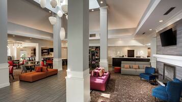 A spacious lobby with a seating area, a bar, and a fireplace.