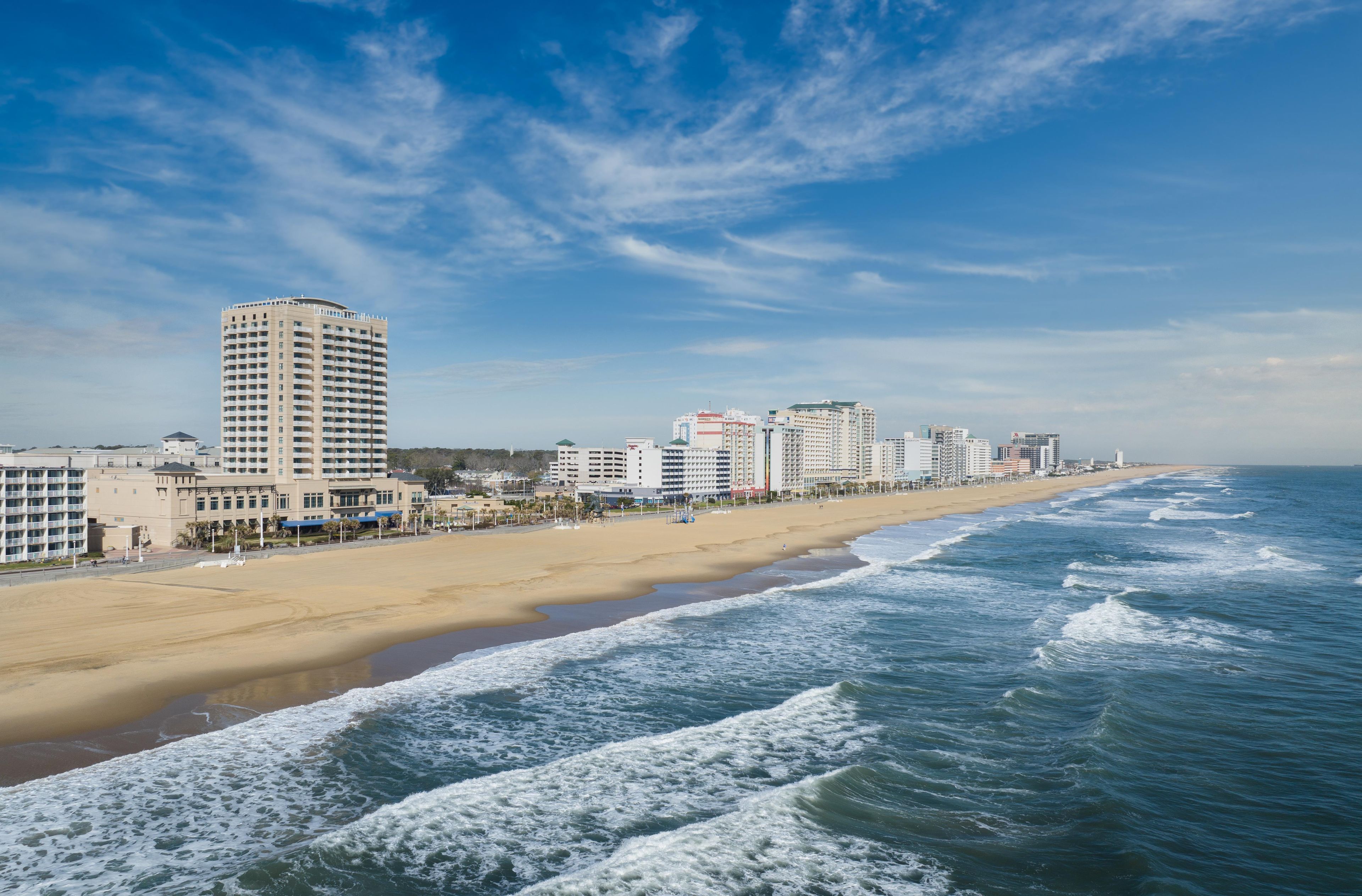 A coastal cityscape with a beach, ocean waves, and high-rise buildings.