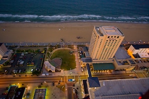 Vue aérienne d’une zone côtière comprenant un hôtel Hilton, une plage et un parking.