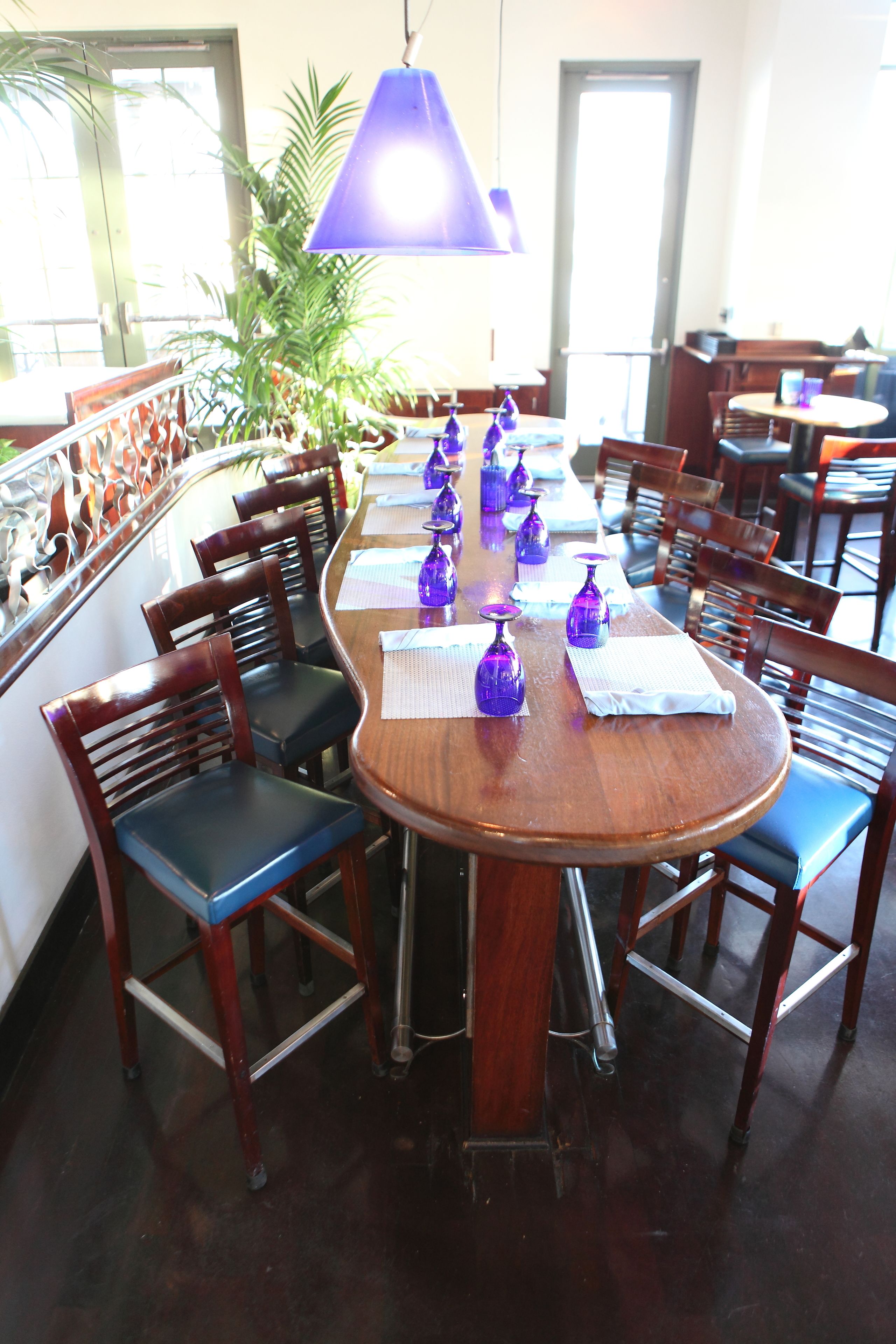 Un coin repas avec une table en bois dressée pour six personnes, entourée de chaises en bois dotées de coussins bleus.