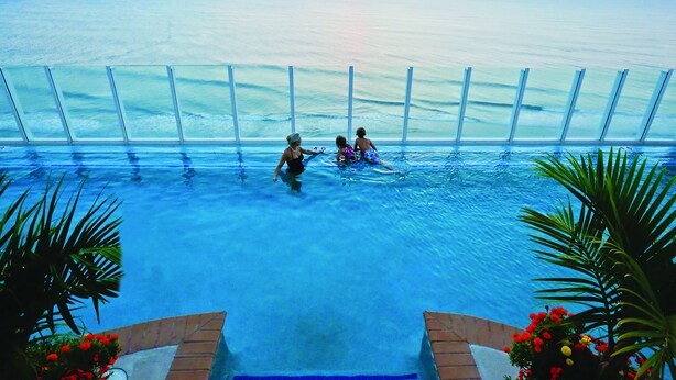 An infinity pool with a view of the ocean at sunset. - Hilton Virginia Beach Oceanfront (Virginia Beach)