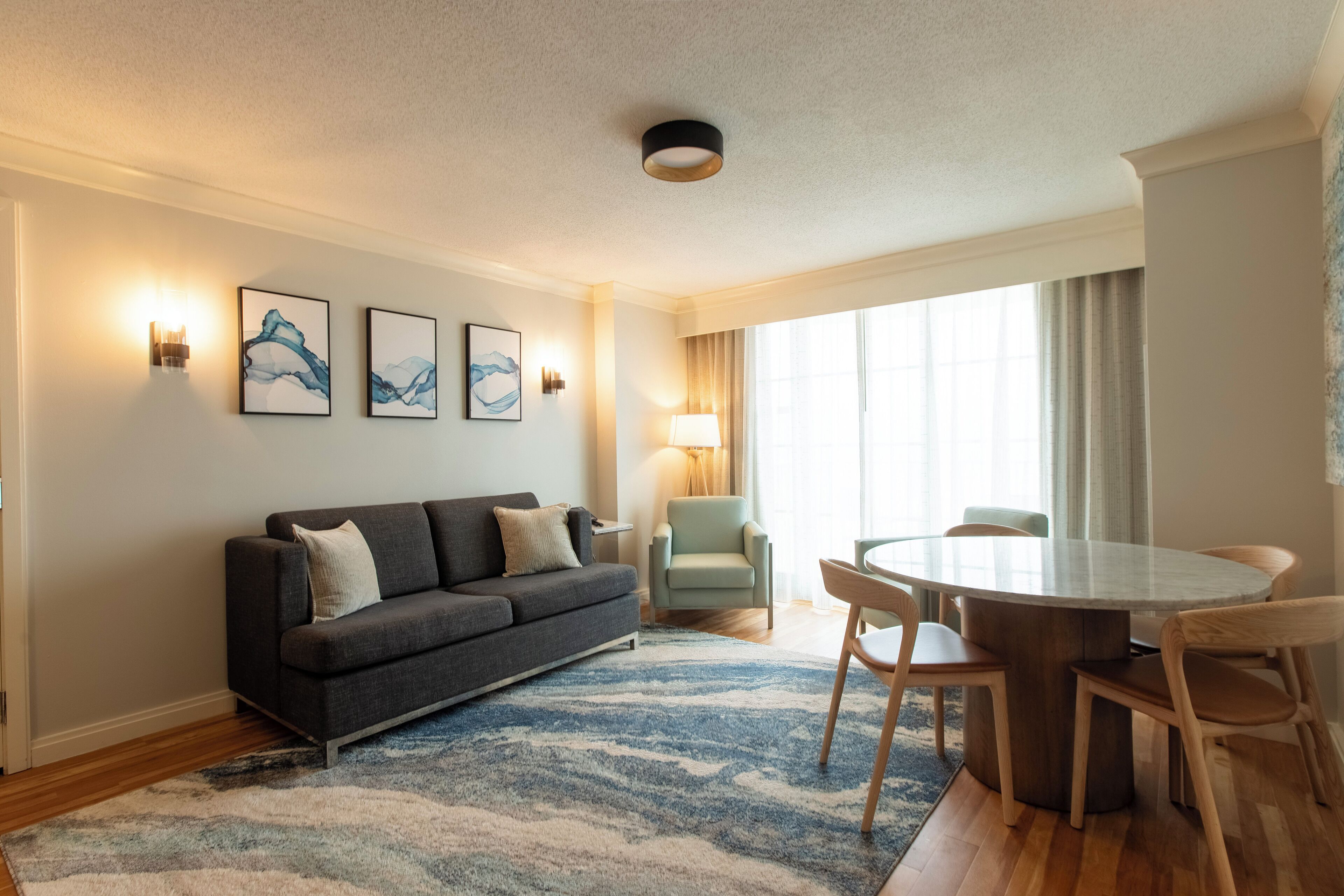 A modern living room with a sofa, a round dining table, and a lamp.