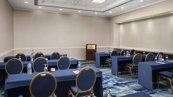 A conference room with multiple tables and chairs, a podium, and a water dispenser.