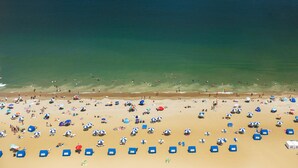 An aerial view of a beach with numerous umbrellas and beach chairs. - Hilton Virginia Beach Oceanfront (Virginia Beach)