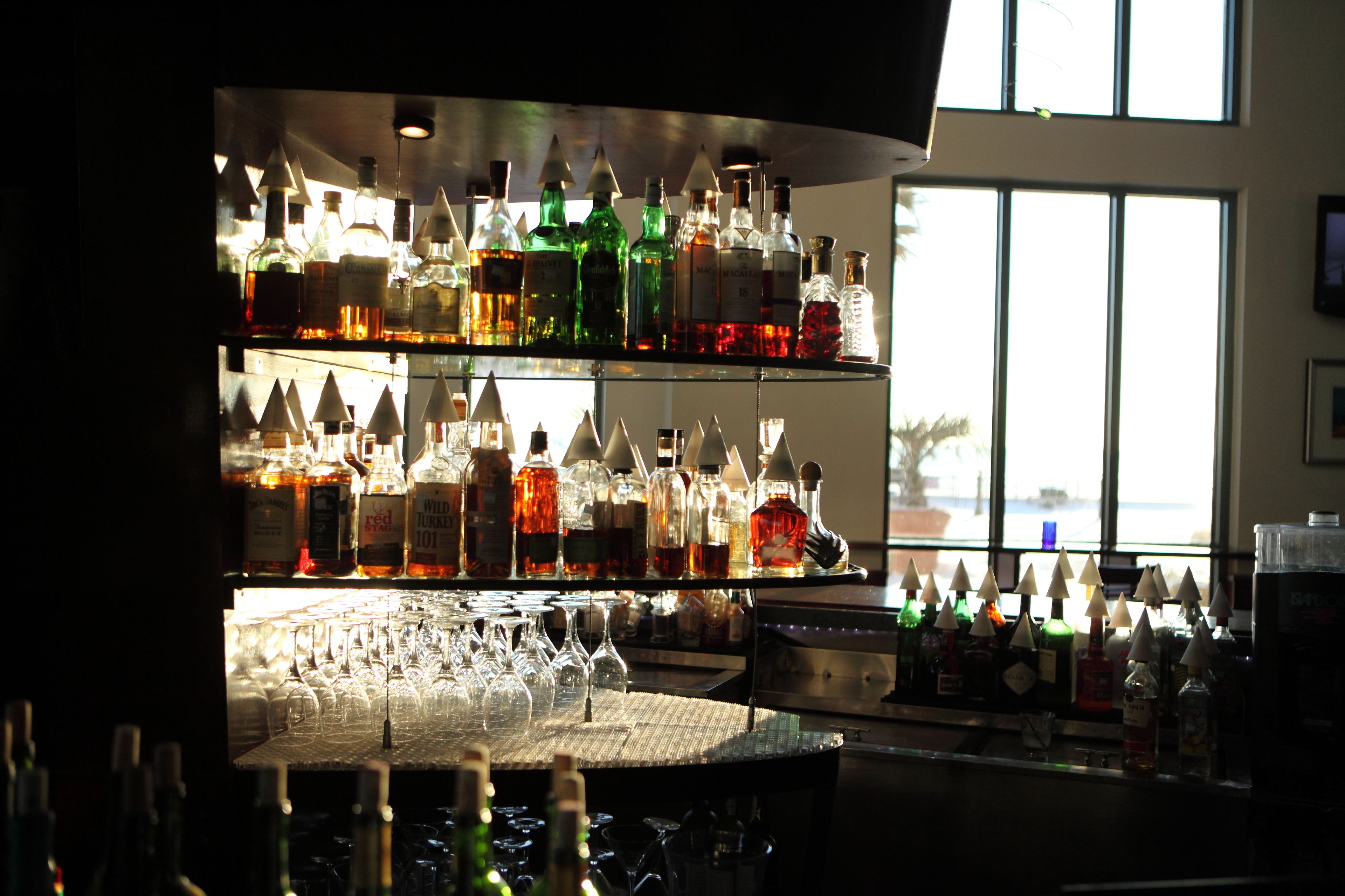 A bar with multiple shelves of liquor bottles and a variety of glasses.