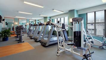 A gym with treadmills, weight machines, and a mirror wall.