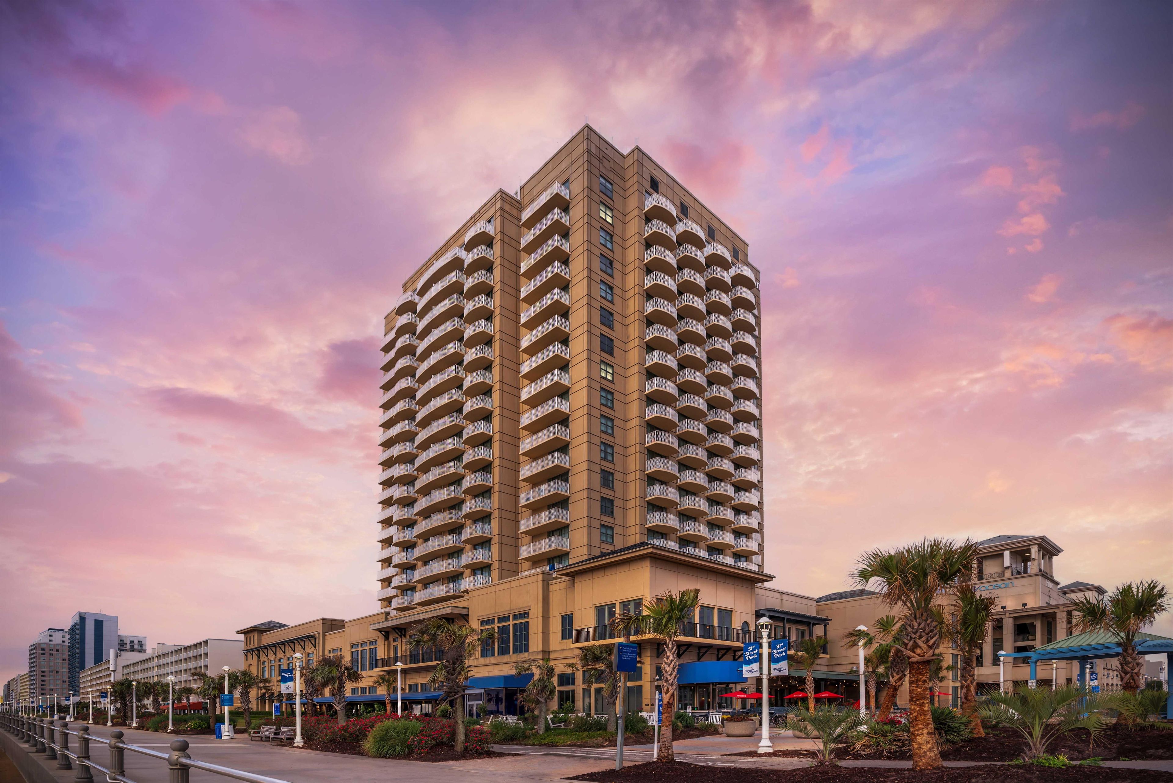 A high-rise hotel with multiple balconies, a landscaped courtyard, and a view of the surrounding urban area.