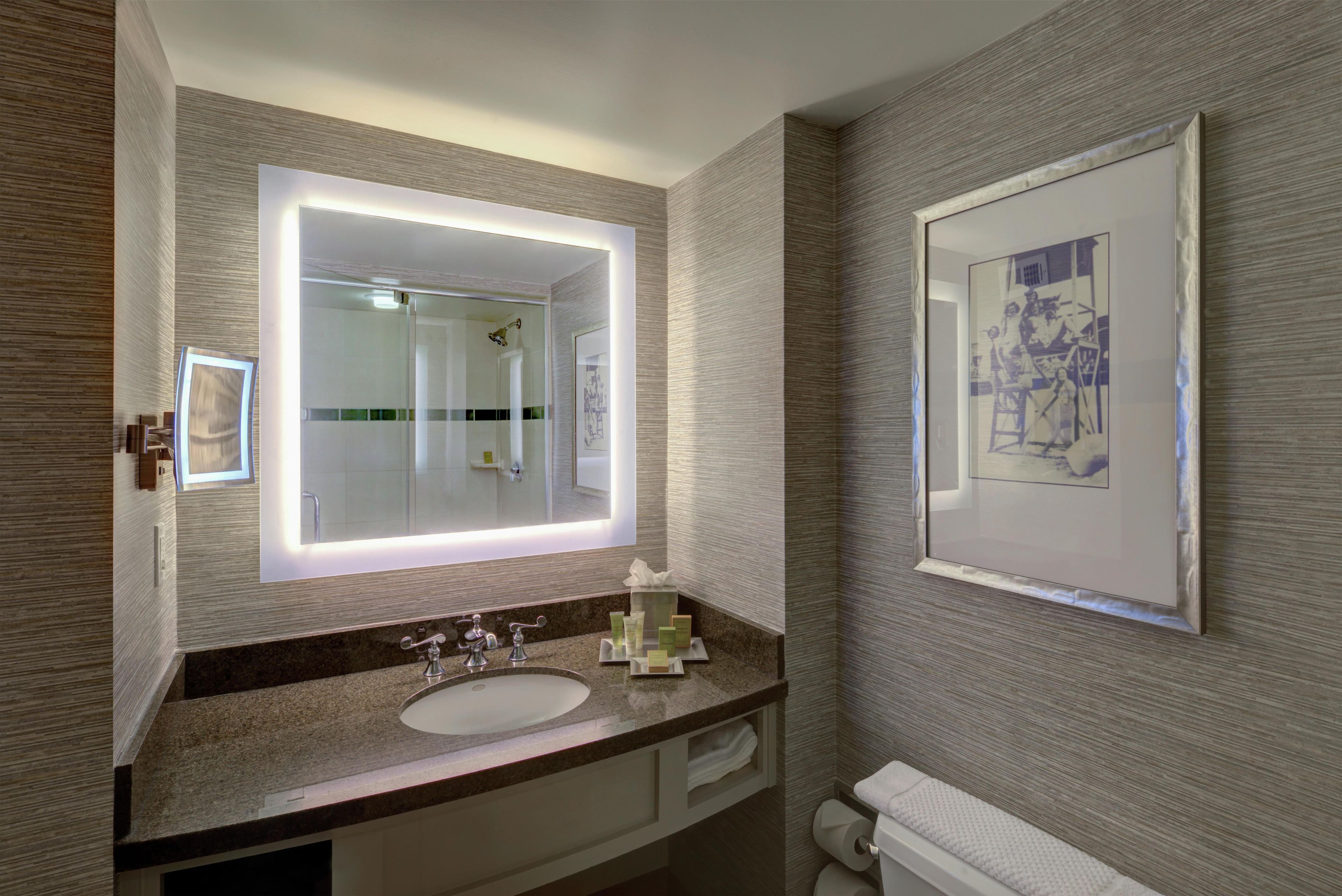 A bathroom with a large mirror, a sink, and a toilet.
