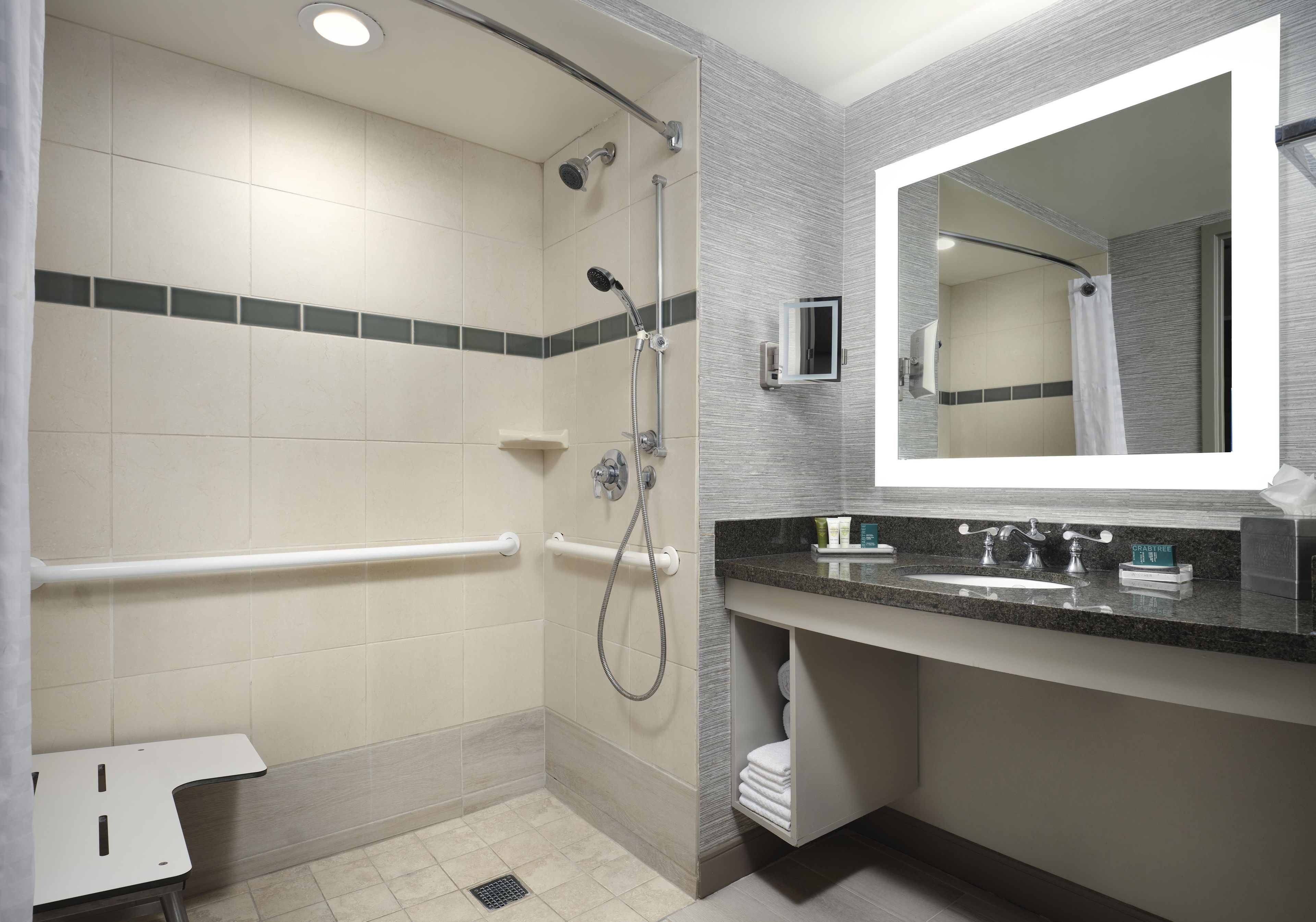 Une salle de bain moderne équipée d’une douche, d’un meuble-lavabo et d’un miroir.