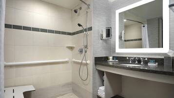 Une salle de bain moderne équipée d’une douche, d’un meuble-lavabo et d’un miroir.