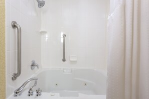 A bathroom with a white bathtub, two faucets, a handheld showerhead, and a grab bar. - Holiday Inn Express Tower Center by IHG (East Brunswick)
