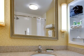 A bathroom with a large mirror, a sink, a shower, and a towel rack. - Holiday Inn Express Tower Center by IHG (East Brunswick)