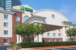 A Holiday Inn Express building with a brick facade, a large curved overhang, and a well-maintained hedge in front. - Holiday Inn Express Tower Center by IHG (East Brunswick)
