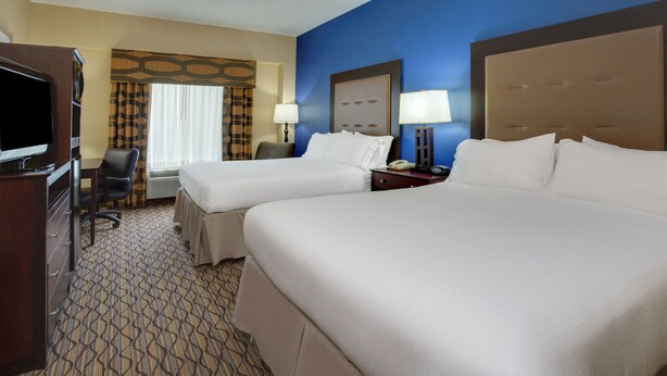 A hotel room with two beds, a desk, a chair, a TV, and a window with curtains. - Holiday Inn Express Tower Center by IHG (East Brunswick)