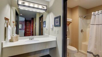 A modern bathroom with a white sink, a large mirror, and a shower area.