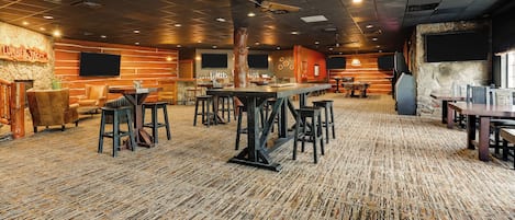 Un amplio espacio interior con diversas opciones de asientos, incluyendo mesas y sillas, y una zona de bar con taburetes.