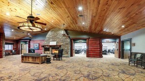 A spacious lobby with a stone fireplace, wooden ceiling, and a patterned carpet. - Stoney Creek Hotel La Crosse - Onalaska (Onalaska)