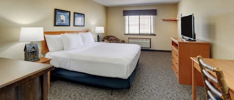 Habitación de hotel con cama, escritorio, televisor y ventana con persianas.